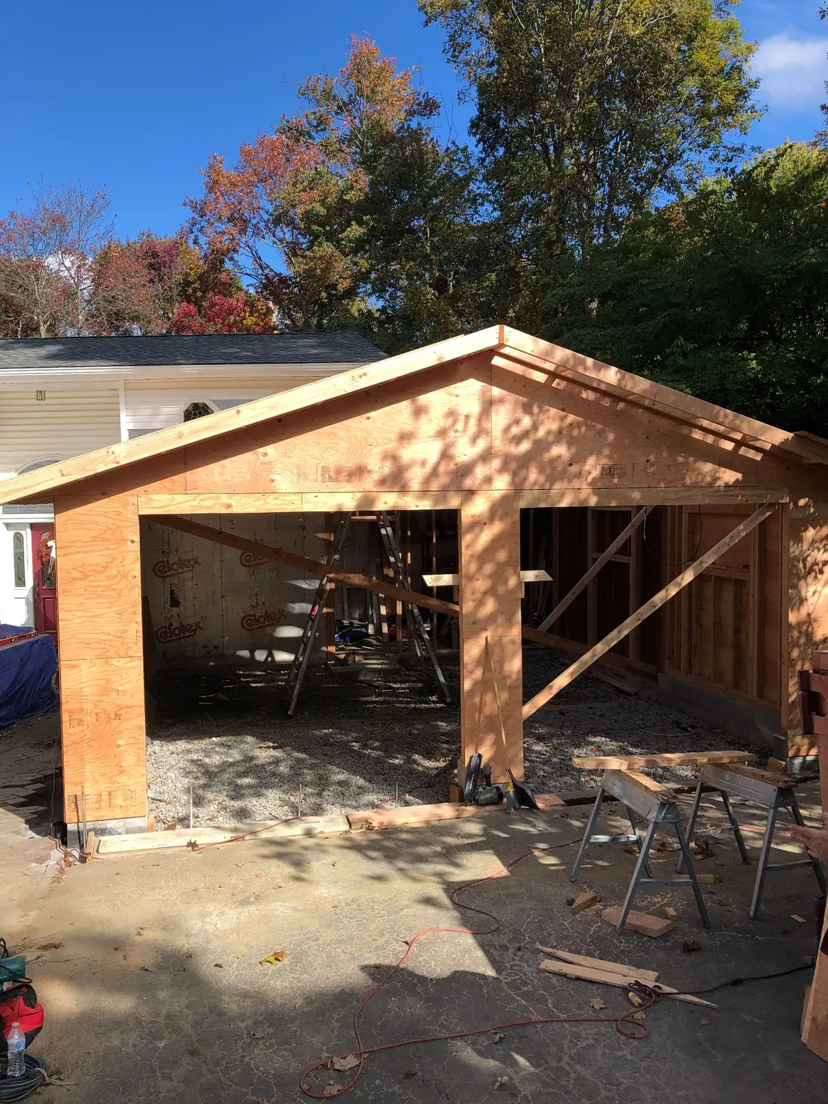 Garage addition framed and sheathed beneath a blue autumn sky